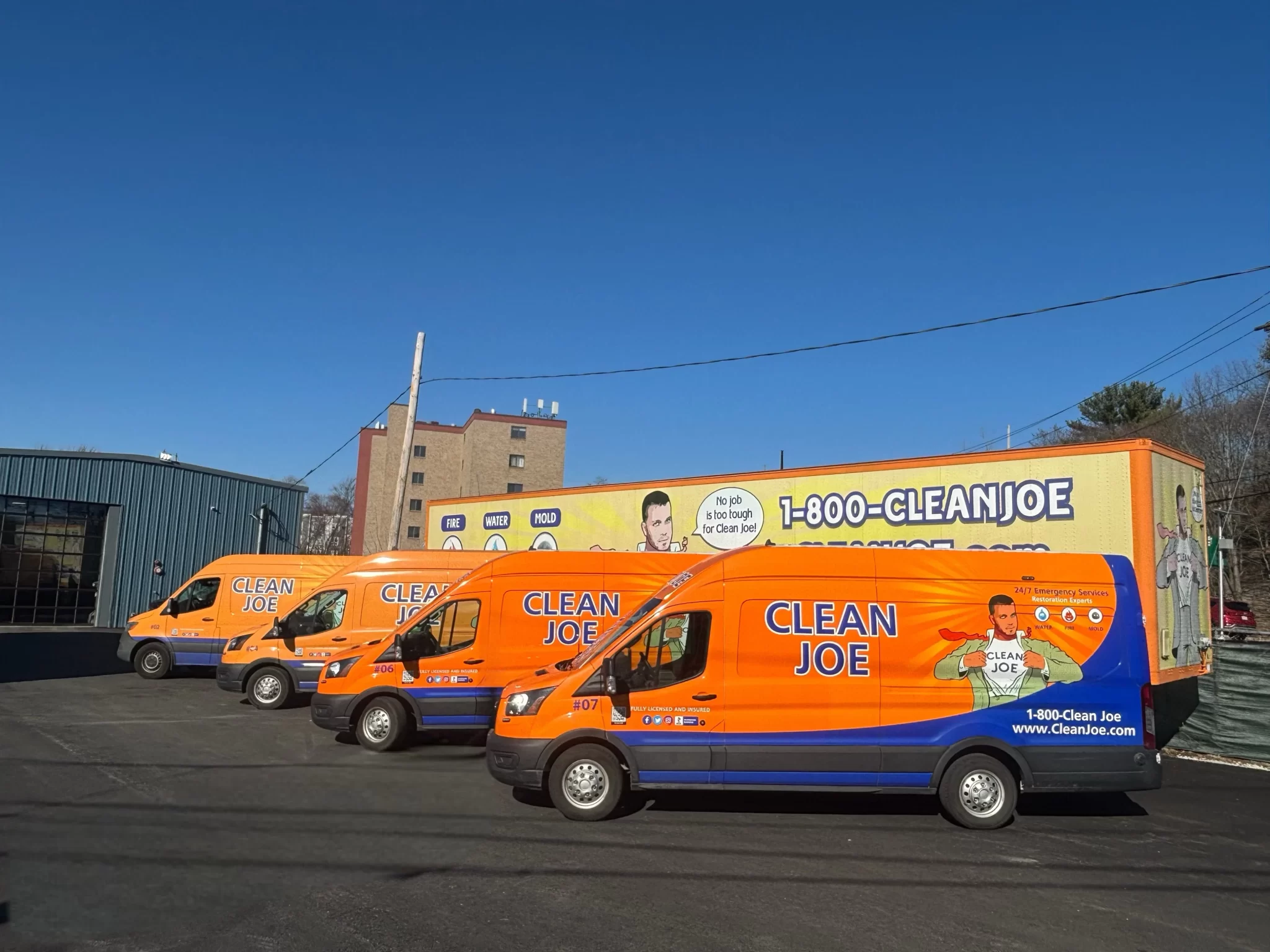 Clean Joe fleet of orange emergency restoration vans parked outside the Revere, Massachusetts shop