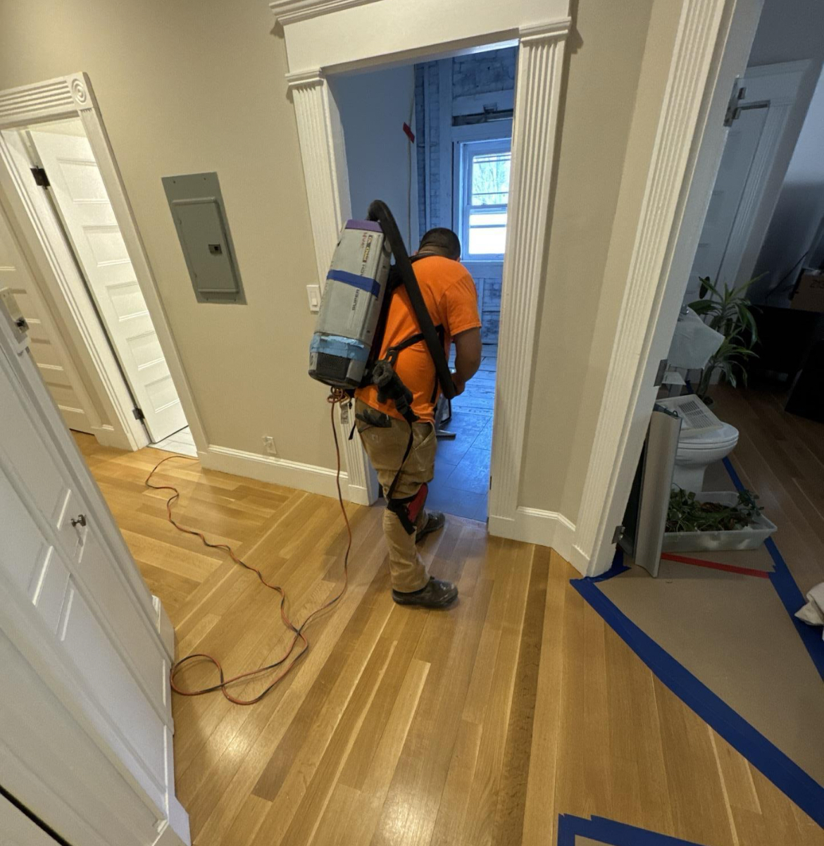 Clean Joe technician using a backpack HEPA vacuum inside a protected Boston home